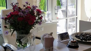 A dining area with a table set for two, a vase of flowers, a teapot, and a bell. - Garni Villa Tyrol - Adults Only (Merano)