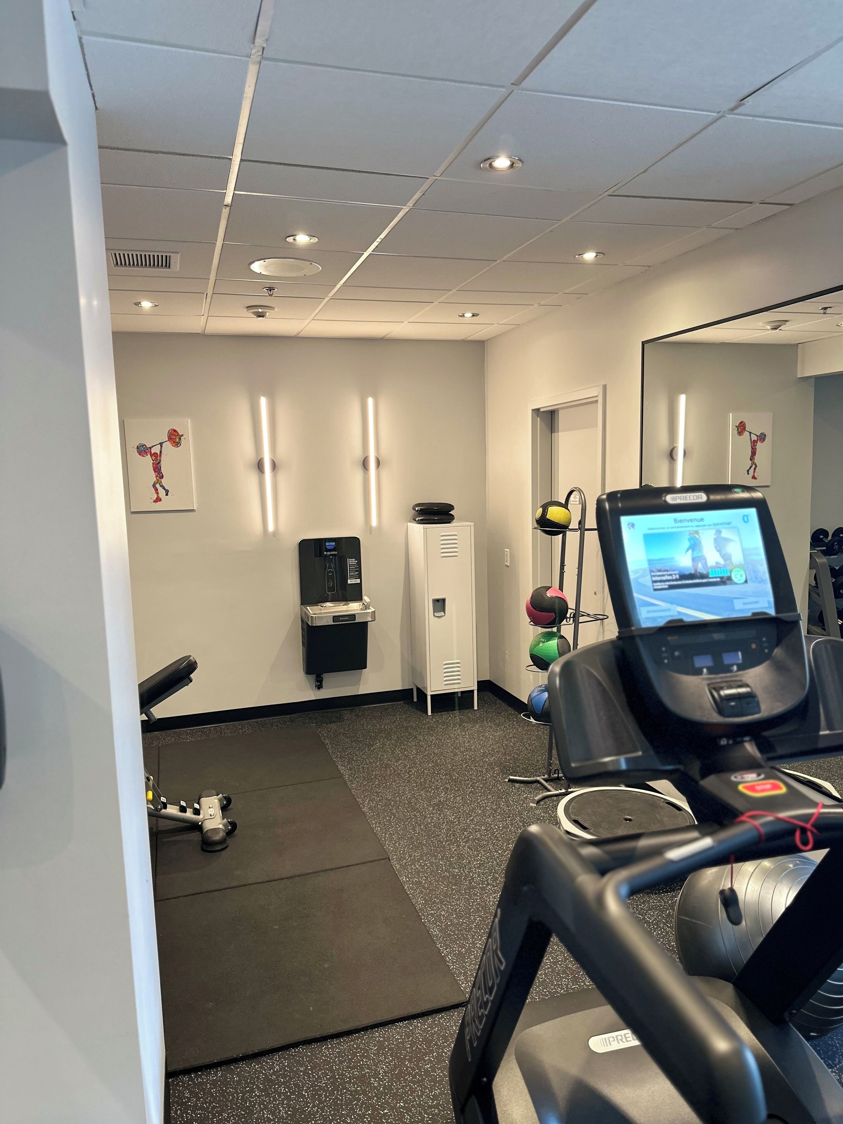 A gym with exercise equipment, a water dispenser, and a treadmill.