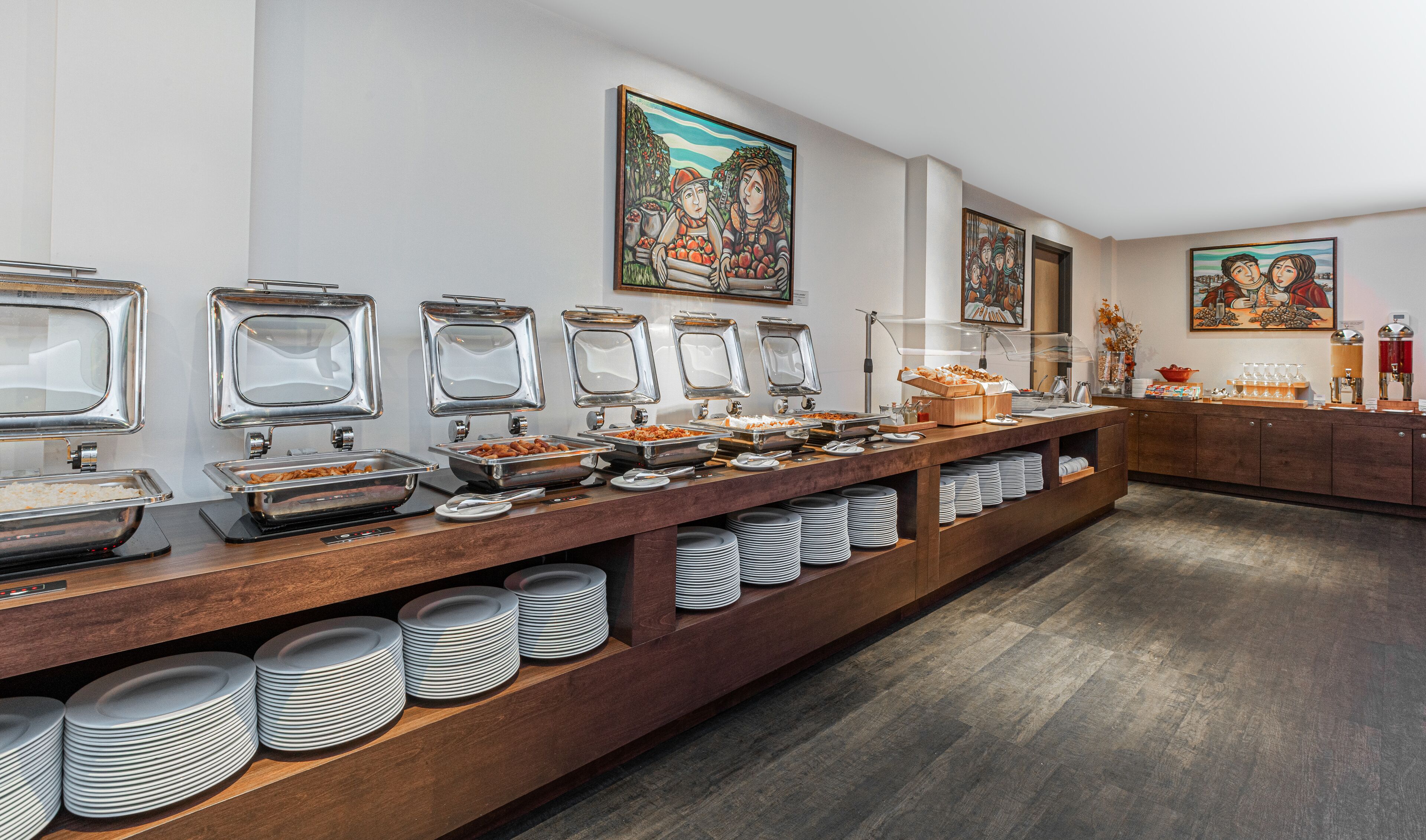 Un buffet composé de plusieurs présentoirs de nourriture, d’un comptoir en bois et de tableaux accrochés au mur.