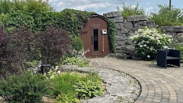 A garden area with a stone wall, a wooden shed, and a paved walkway.