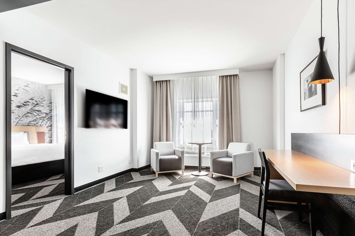 Et moderne hotelværelse med en seng, to lænestole, et lille bord og et spisebord.