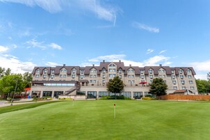 A large hotel with multiple floors, a well-maintained lawn, and a clear sky.