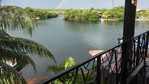 Une rivière aux couleurs de l’arc-en-ciel, bordée de verdure et avec une maison à proximité.