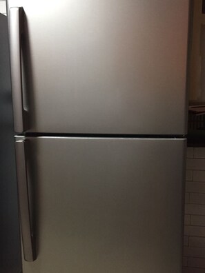A stainless steel refrigerator with a freezer compartment on top and a main compartment below.