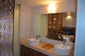 Un baño con dos lavamanos, un espejo y una bandeja de madera.