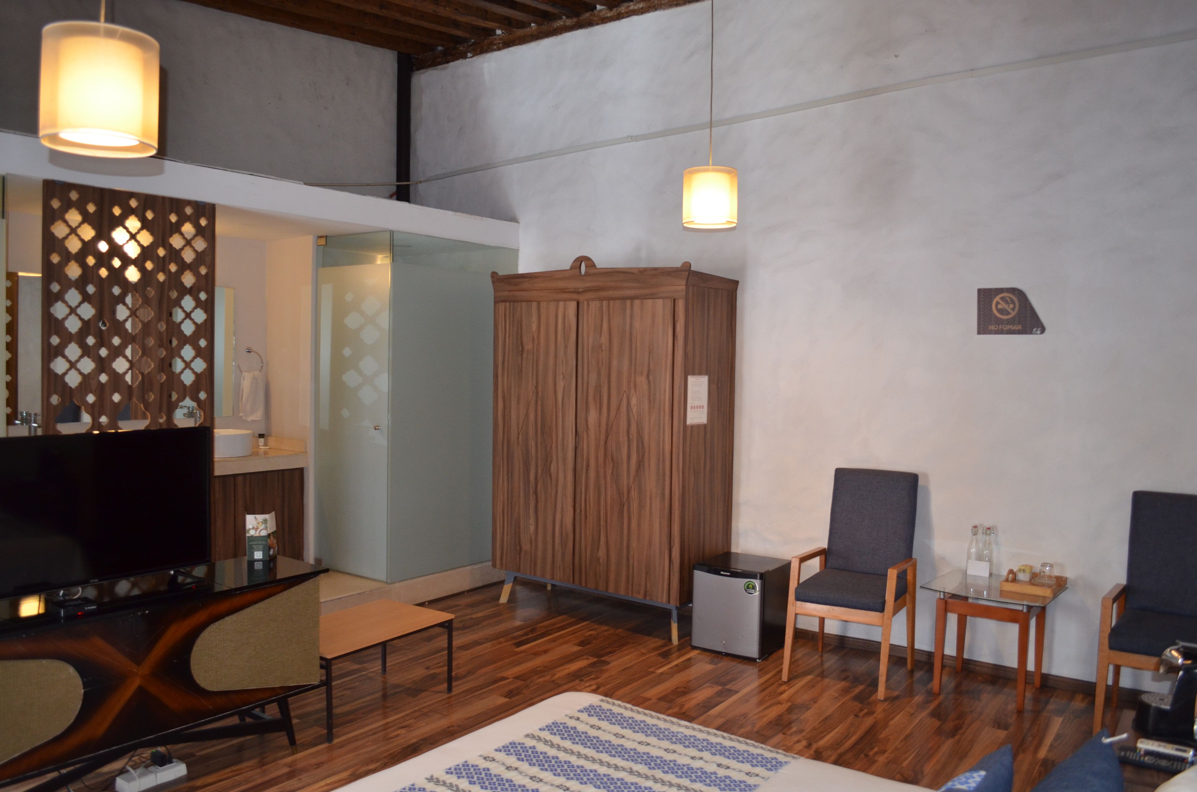 A modern room with a wooden cabinet, a television, and two chairs.