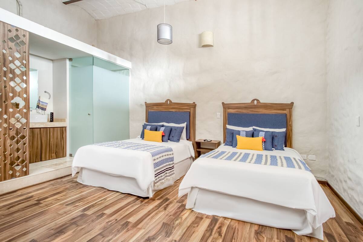 A room with two beds, wooden headboards, and a wooden floor.