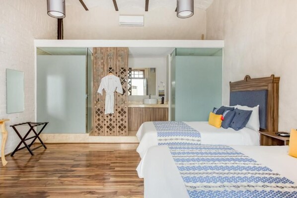 Una habitación de hotel con cama, mesita de noche y piso de madera.