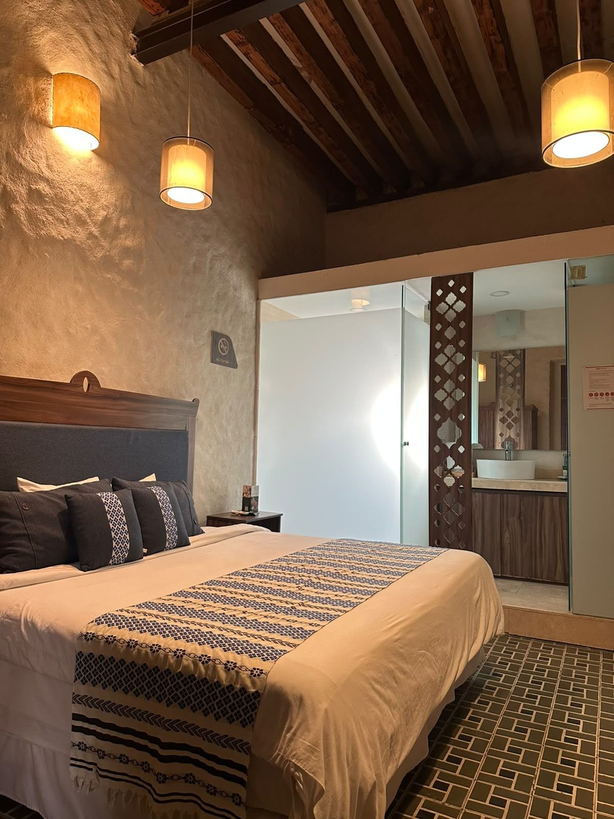 Ein Schlafzimmer mit einem Bett, Nachttischen und einem durch eine offene Tür einsehbaren Badezimmer.