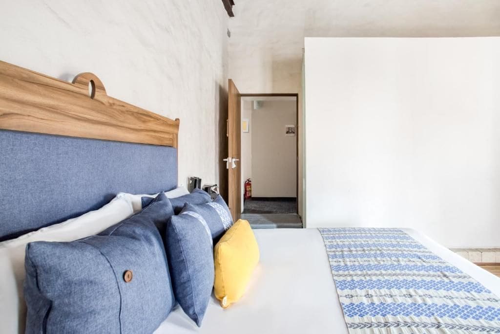 A bedroom with a bed, pillows, a headboard, and a patterned bedspread.