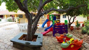 Zona de juegos infantiles con tobogán, estructuras para escalar y una pequeña piscina.