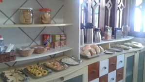 A buffet setup with various food items and condiments. - Pousada Raio de Sol (Fernando de Noronha)