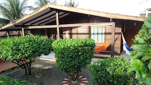 A wooden building with a covered patio area, surrounded by well-maintained greenery and a decorative stone pattern. - Pousada Raio de Sol (Fernando de Noronha)