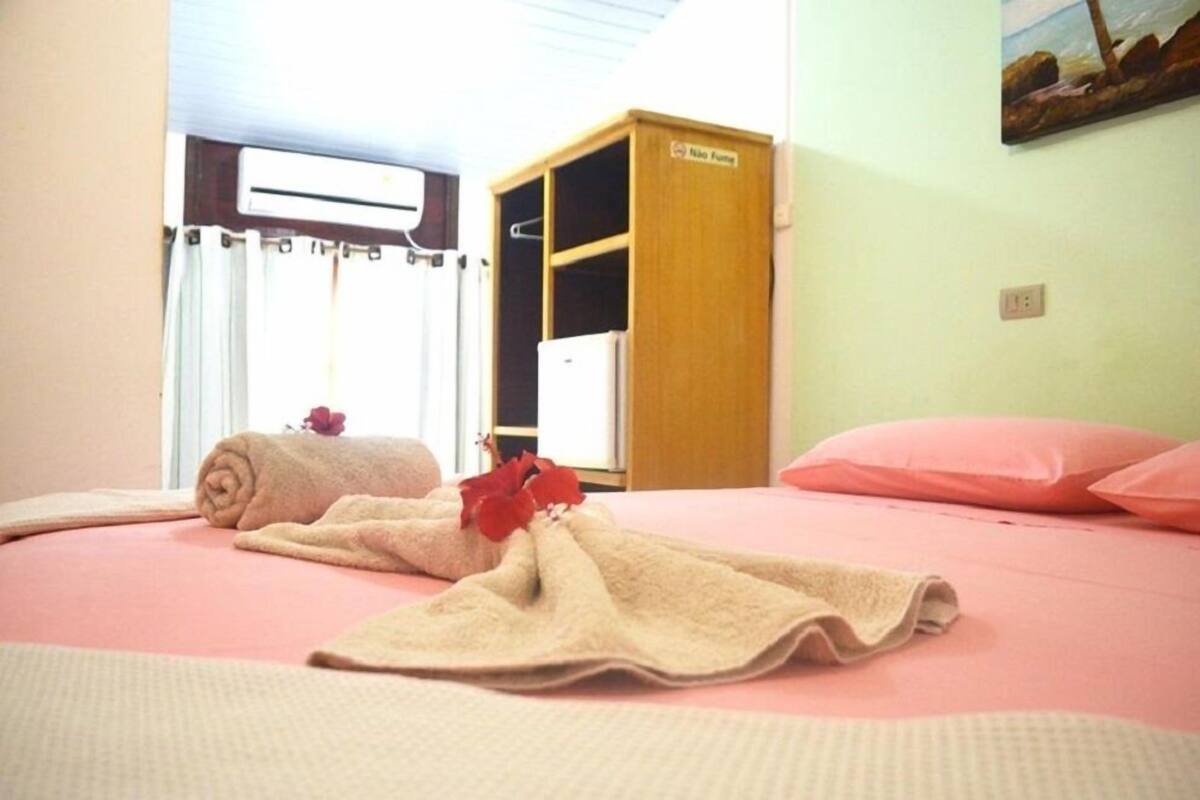 Ein Zimmer mit einem Bett, einem Holzschrank, einem Fenster mit Vorhängen und einem Bild an der Wand.