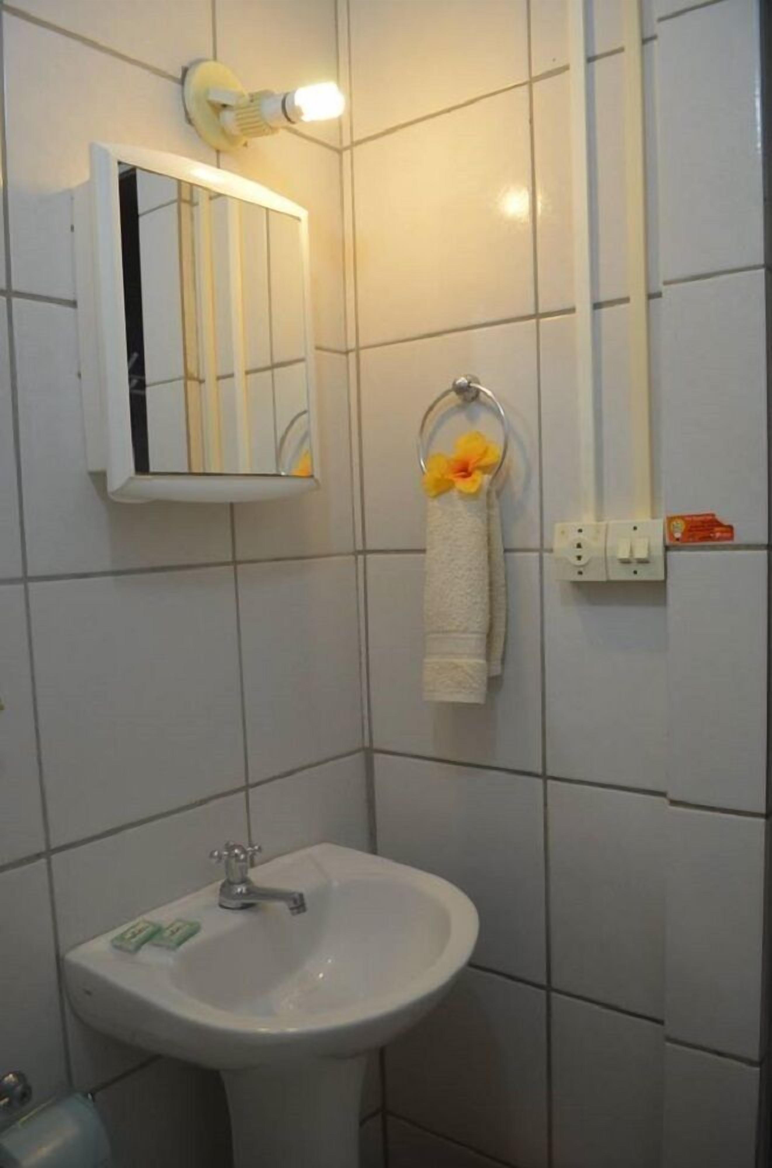 Un bagno con un lavandino bianco, uno specchio e un portasciugamani con un fiore.