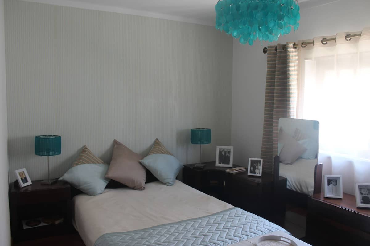 A neatly arranged bedroom with a bed, two bedside tables, and a hanging light fixture.