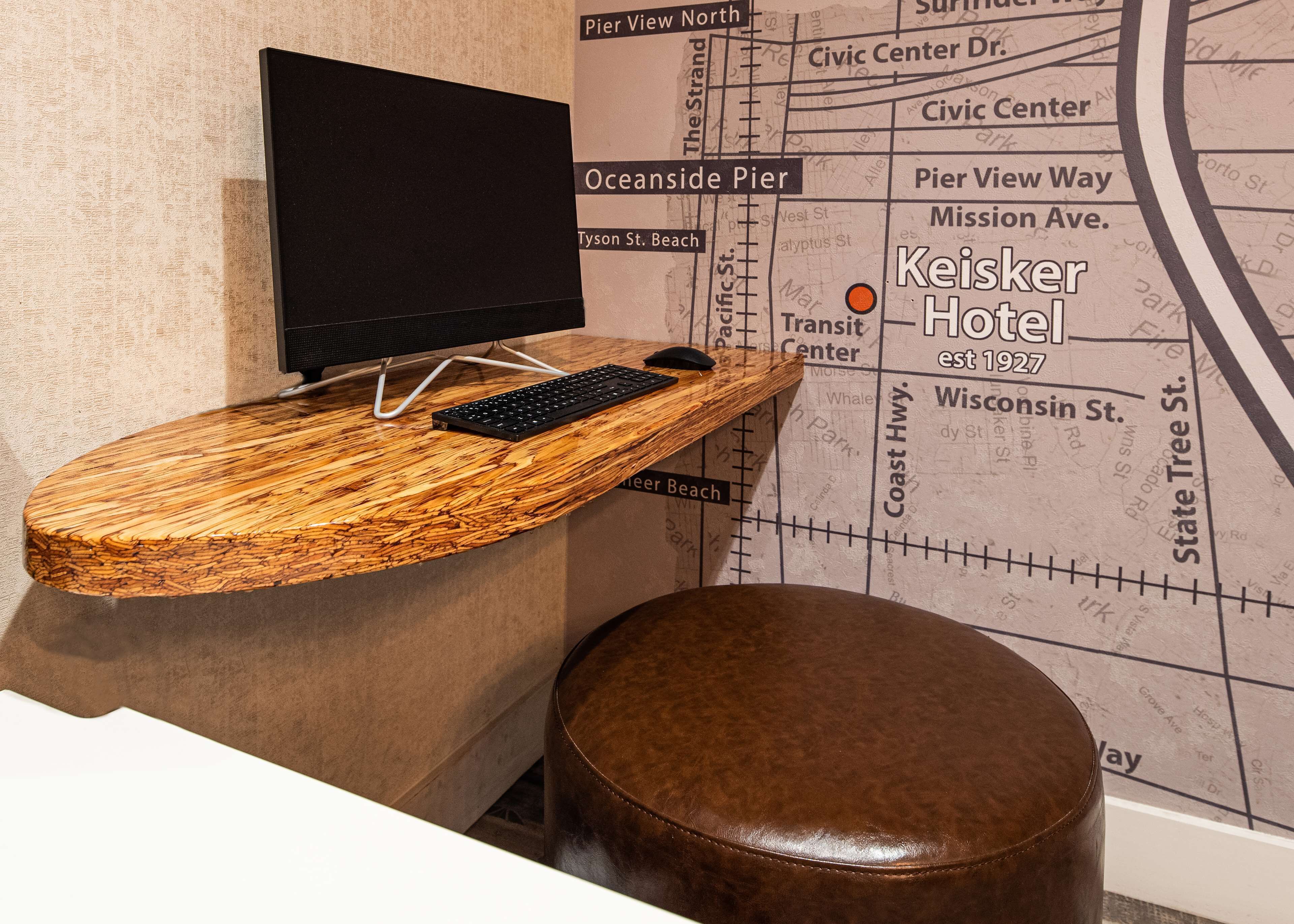 A unique room with a wooden desk, a black monitor, and a brown leather stool.