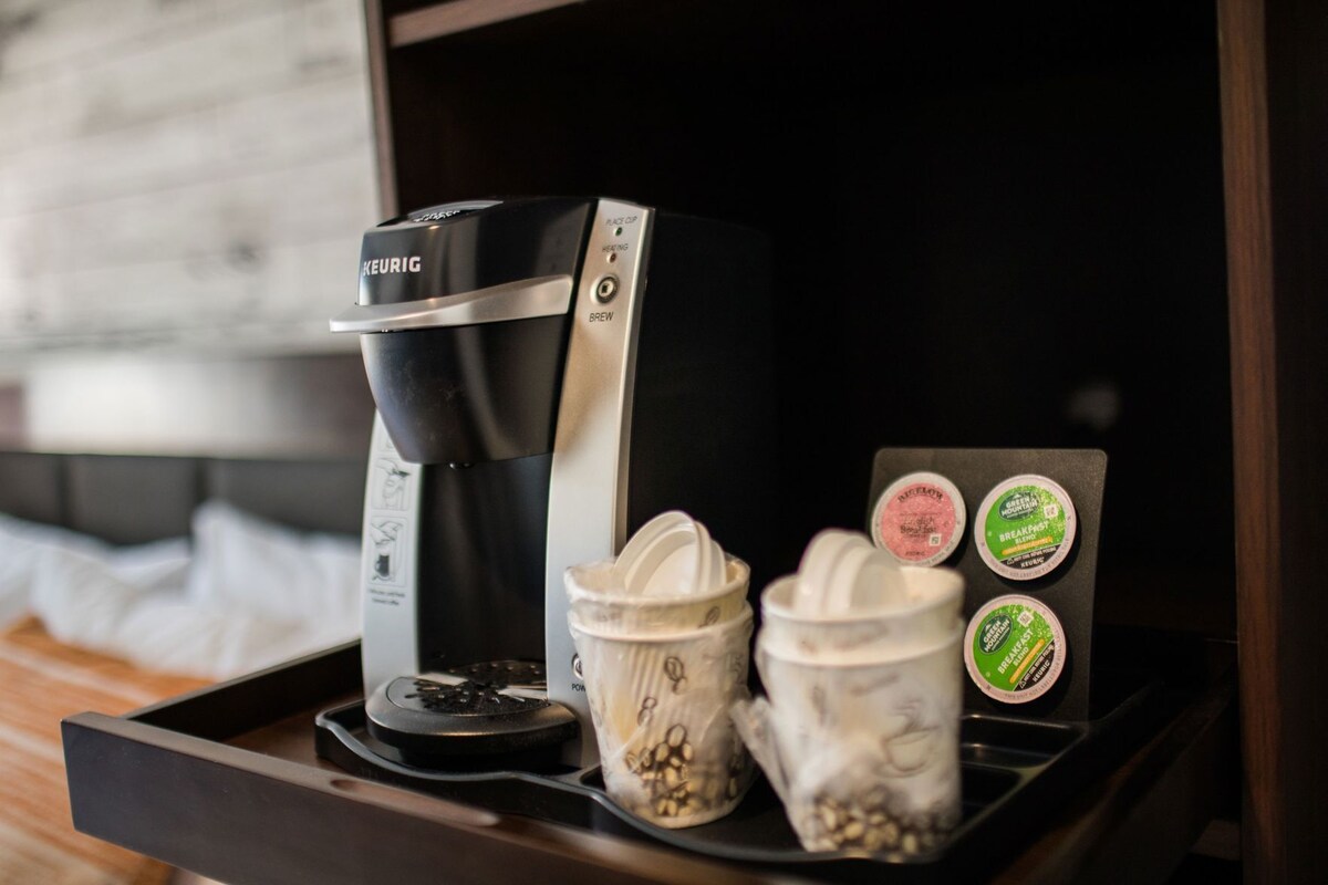 A Keurig coffee maker on a tray with two coffee pods and two coffee mugs.