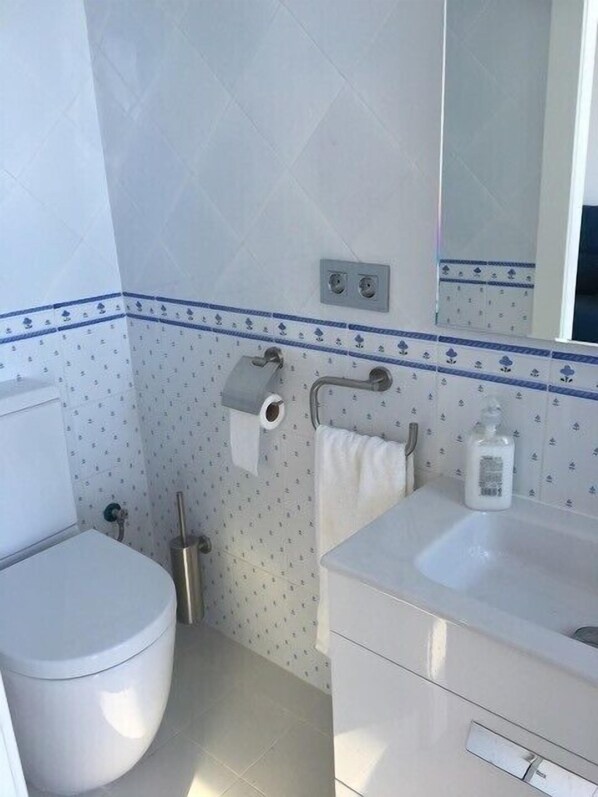 A bathroom with a toilet, sink, mirror, and towel rack. - Blue sea front by Hello Homes Sitges (Sitges)