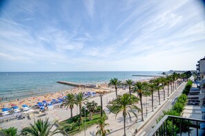 Ein Hotel am Strand mit Meerblick, eine Palmengalerie und Strandstühle.