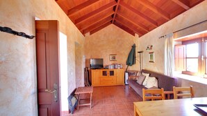 A cozy kitchen with wooden cabinets, a dining table, and a television. - Traditional rural house, tranquility, landscape, renewable energy and WIFI (Taibique)