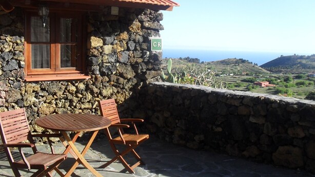 A stone building with a tiled roof, a window with curtains, and a view of the landscape. - Traditional rural house, tranquility, landscape, renewable energy and WIFI (Taibique)
