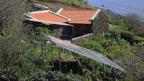 A house with a red-tiled roof, stone walls, and a solar panel. - Traditional rural house, tranquility, landscape, renewable energy and WIFI (Taibique)