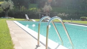 En swimmingpool med en tydlig kant mot vattnet, ett kaklat poolområde och en metallstege.