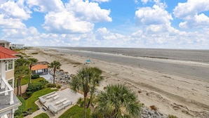 A beachfront property with a large house, a pool, and a beach view.