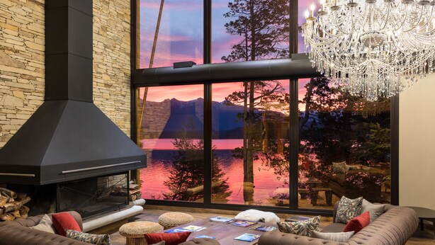 A modern living room with a fireplace, comfortable seating, and a large window offering a scenic view. - Calfuco Wine Hotel & Spa (Villa La Angostura)