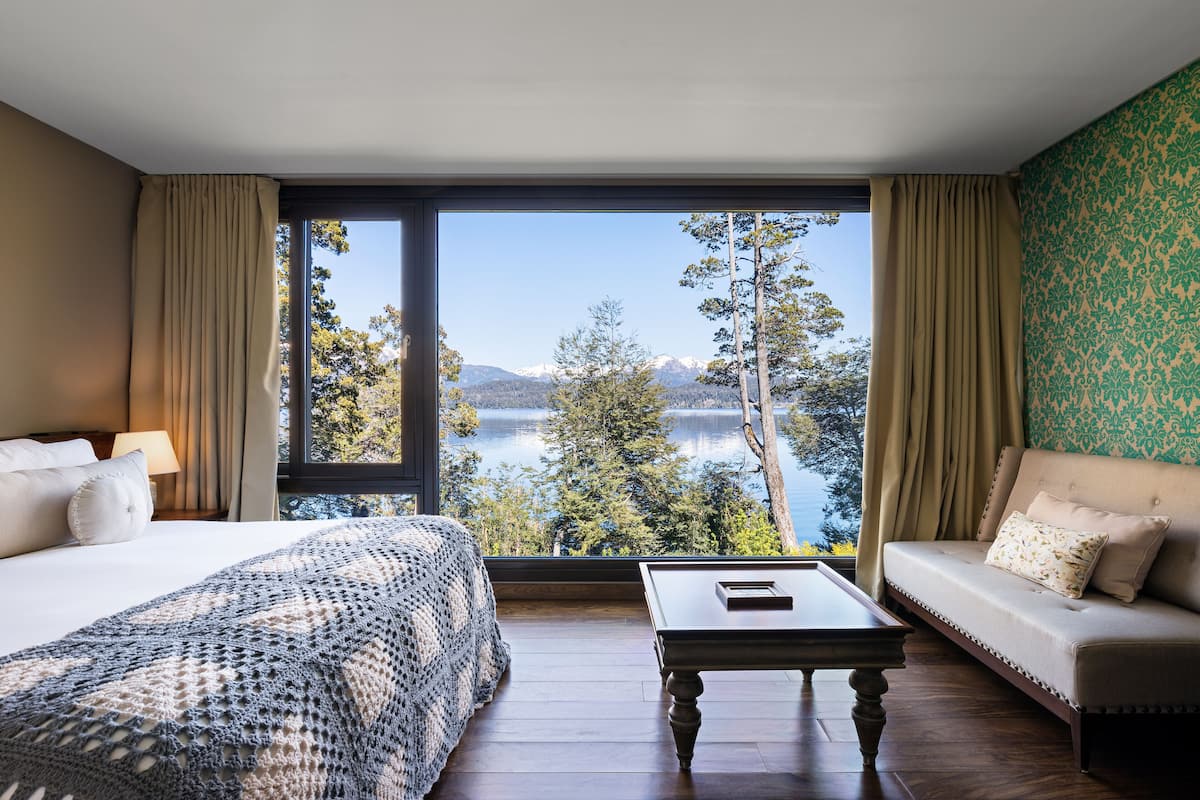 Ein Schlafzimmer mit großem Fenster, einem Bett, einer Couch und einem Couchtisch.
