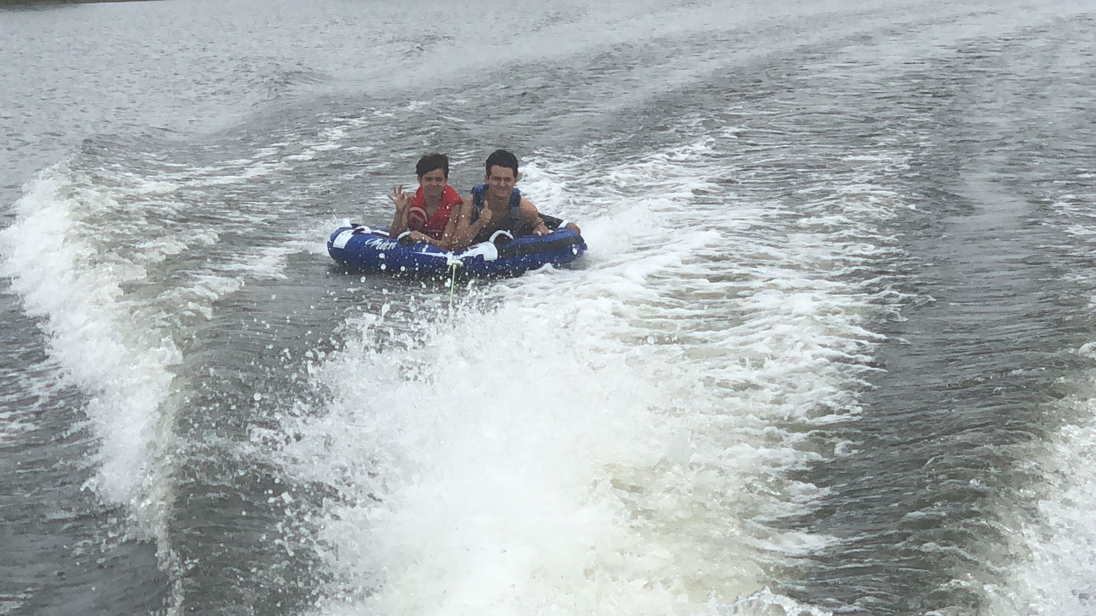 Deux personnes se trouvent dans un radeau gonflable bleu et le font avancer sur l’eau.