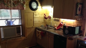 Una cocina con armarios de madera, un lavamanos, un reloj y una decoración de gallo.