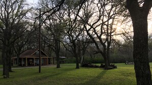 Una cabaña rústica con un porche y una mesa de picnic en un parque cubierto de césped.