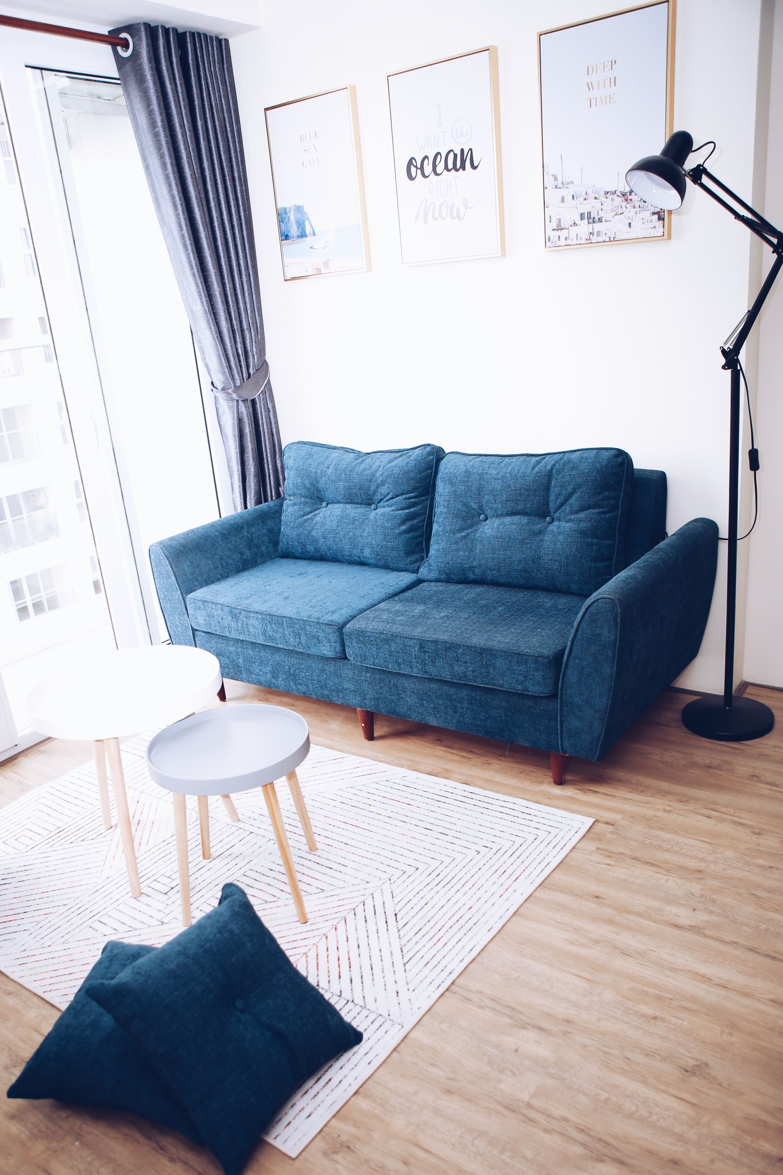 A modern living room with a blue sofa, a small white table, and a floor lamp.