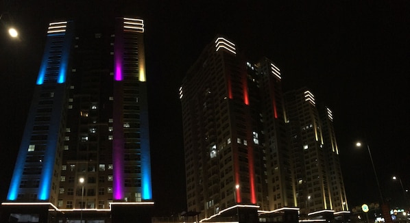 A nighttime view of high-rise buildings with illuminated windows and architectural lines.