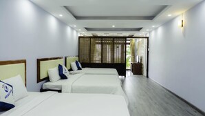 A hotel room with three beds, a wooden headboard, and a view through a bamboo screen to the outside. - Ho May Resort (Ho Chi Minh City)