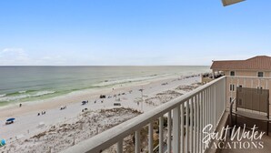 A beach view from a balcony overlooking a sandy beach with a few people and beach chairs. - Inn at Crystal Beach 608b * Gulf Front with Beach Chair Set. Onsite dining! (Destin)
