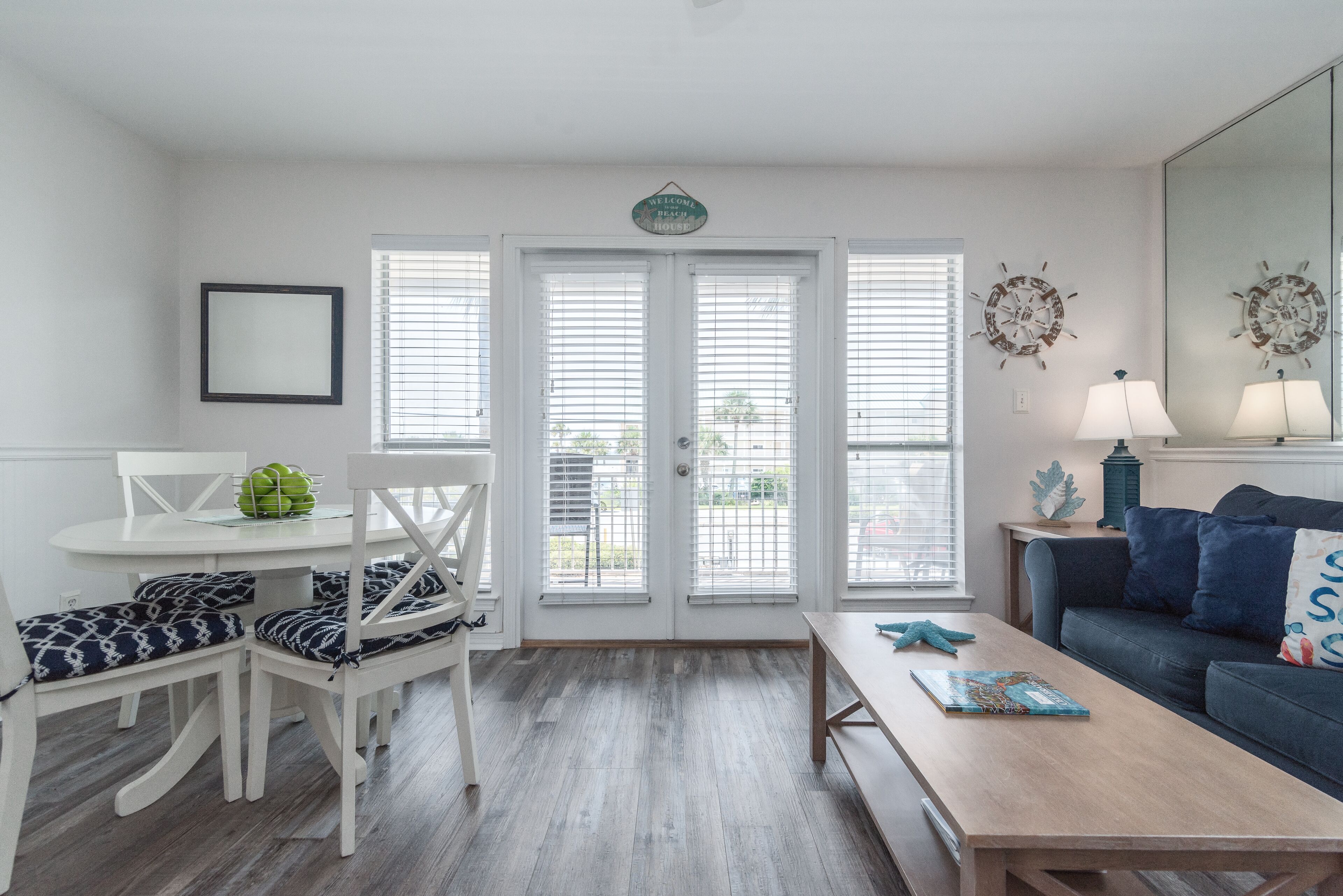 Een woonkamer met een witte eettafel, stoelen met blauw-witte patronen, een blauwe bank en een houten salontafel.