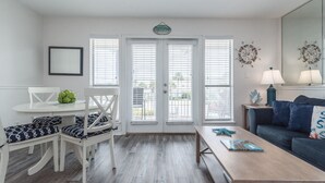 A living room with a white dining table, blue and white patterned chairs, a blue sofa, and a wooden coffee table.