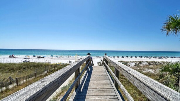 A wooden boardwalk leading to a beach with clear skies.