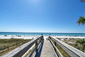 A wooden boardwalk leading to a beach with clear skies.