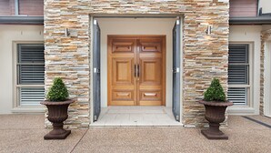 Une porte en bois à deux battants, dotée d’une façade en pierre et flanquée de deux plantes en pot.