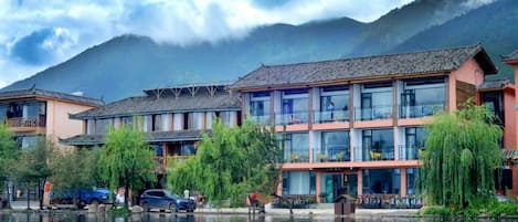Un bâtiment traditionnel à étages, doté de grandes fenêtres et dont l’image se reflète dans l’eau.