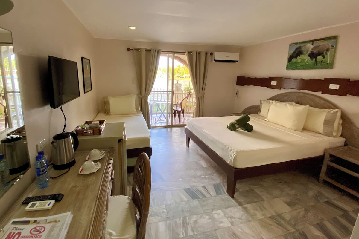 A hotel room with a bed, a desk with a chair, a television, a coffee maker, and a view of the outdoors.