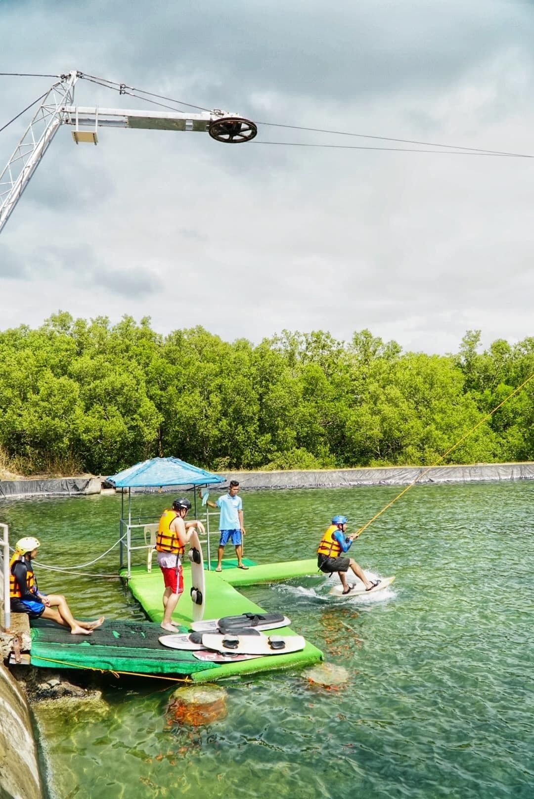 A water activity area with a green platform, ropes, and people engaging in water sports.