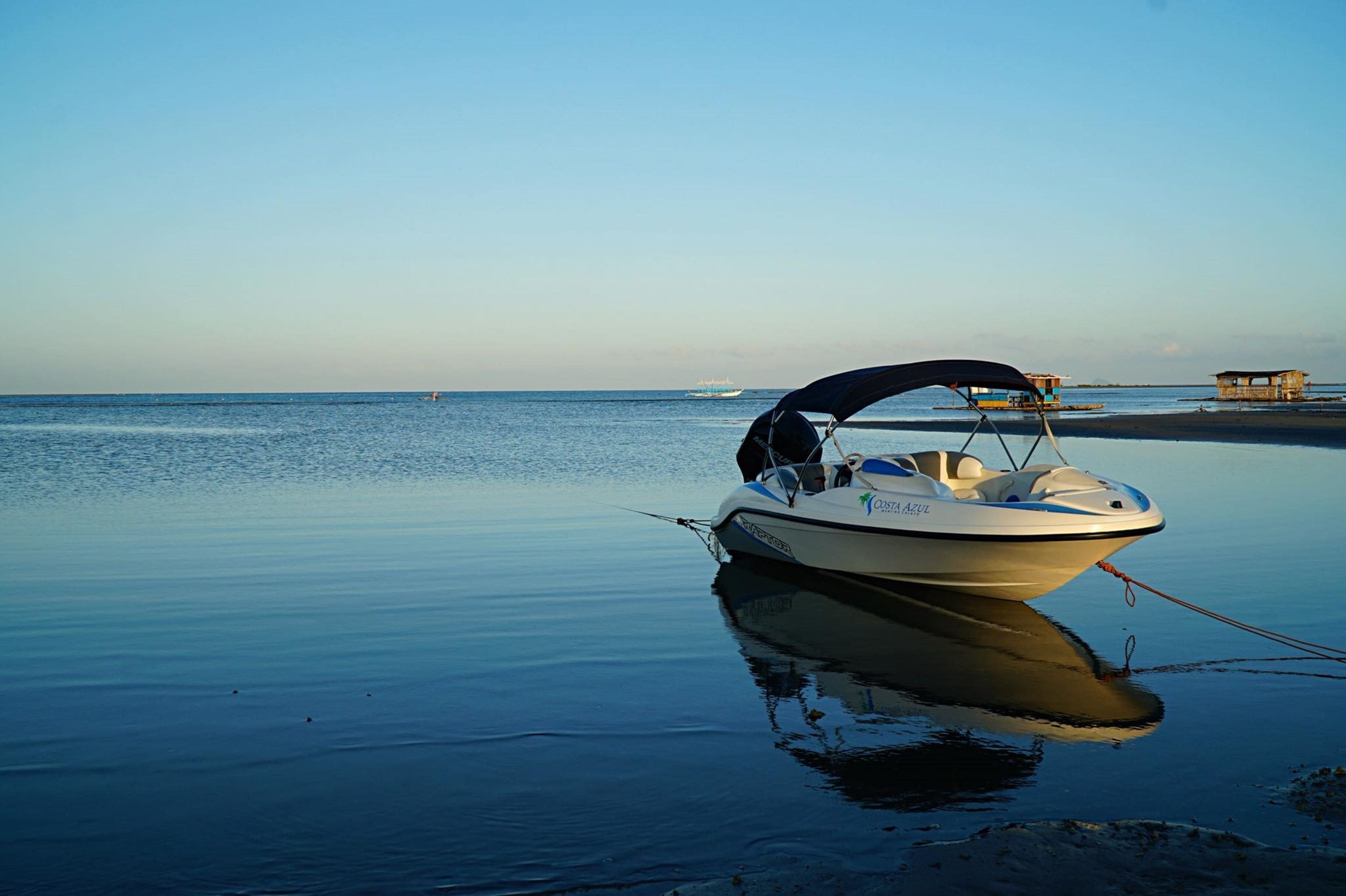 Un bateau était amarré près d’une plage tranquille, sous un ciel dégagé.