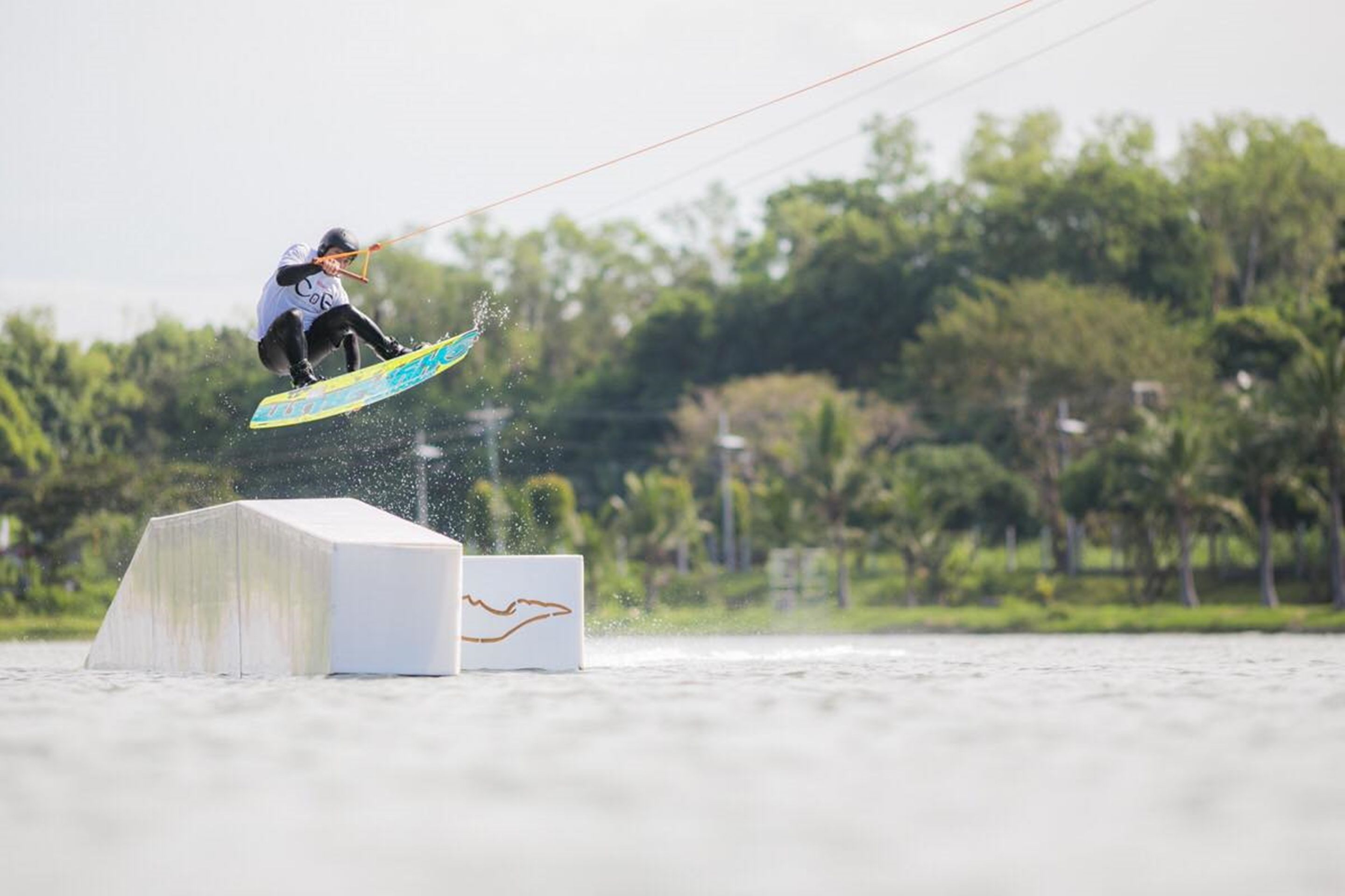 A wakeboarder performing a jump over a ramp.