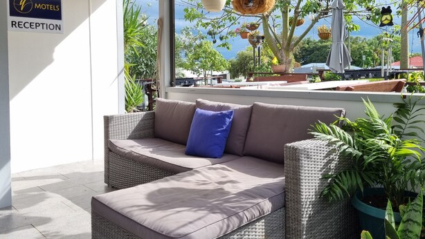 A reception area with a wicker sofa, a blue pillow, and a sign for 'MOTELS RECEPTION'. - Y Motels Yarraman (Yarraman)