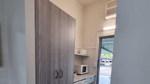 A kitchen with a grey wardrobe, a microwave, and a small sink. - Y Motels Yarraman (Yarraman)